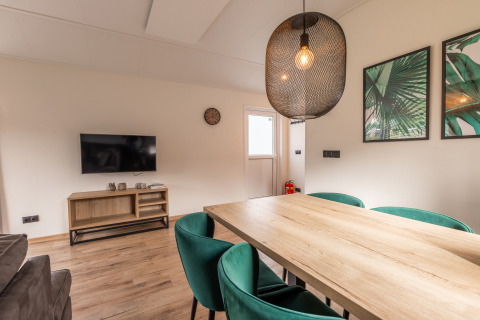 Woonkamer in Velthorst-lodge bij Holiday park Aan de Maas, Nederland, met houten tafel en tv.