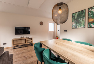 Salon du lodge Velthorst au Holiday park Aan de Maas, Pays-Bas, avec table en bois et déco moderne.