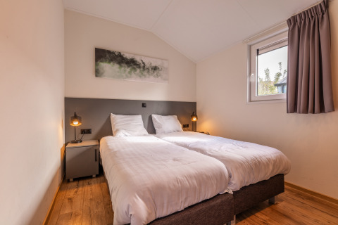 Moderne slaapkamer met twee eenpersoonsbedden in lodge Velthorst, Holiday park Aan de Maas, Nederland.