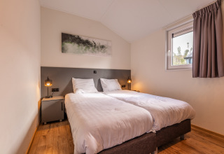 Chambre moderne avec deux lits simples au lodge Velthorst, Holiday park Aan de Maas, Pays-Bas.
