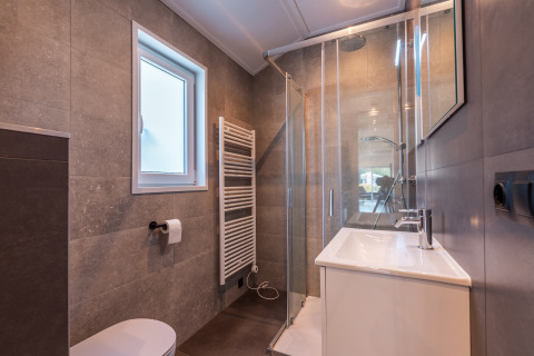 Bagno moderno nella lodge Velthorst, Holiday park Aan de Maas, Paesi Bassi, con doccia e finestra.