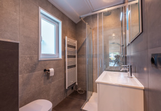Modern bathroom at Velthorst lodge, Holiday park Aan de Maas, Netherlands, with walk-in shower and window.