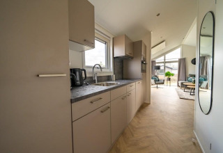 Moderne minihus-køkken og stue med store vinduer, set i Velthorst, Holiday park Aan de Maas, Holland.