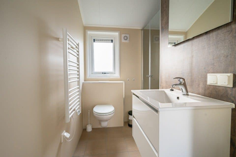 Modern bathroom inside the tiny house 'Velthorst' at Holiday park Aan de Maas in the Netherlands, featuring a sink and toilet.