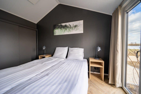 Dormitorio moderno en la tiny house Velthorst, Holiday park Aan de Maas, Países Bajos, con vista exterior.