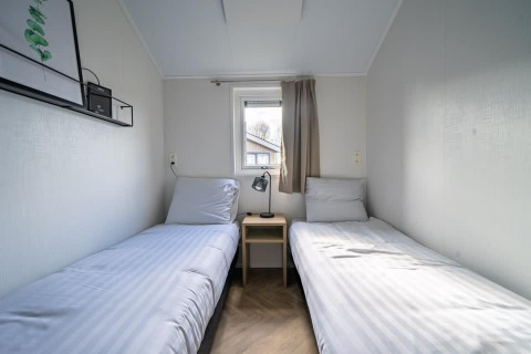 Minimalistische slaapkamer met twee aparte bedden in het Velthorst tiny house bij Aan de Maas, Nederland.