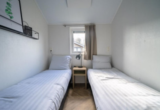 Minimalist bedroom in Velthorst tiny house with twin beds, located at Holiday park Aan de Maas, Netherlands.