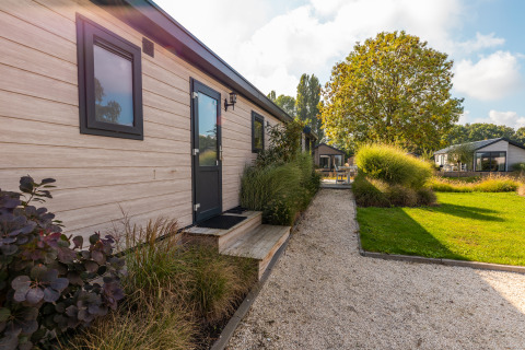 Blick auf den Weg und Garten am Tiny House 'Velthorst' im Ferienpark Aan de Maas, Niederlande.