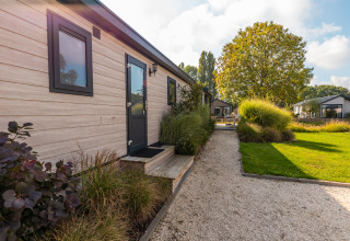 View of the path and garden beside the tiny house 'Velthorst' at Holiday park Aan de Maas, Netherlands.