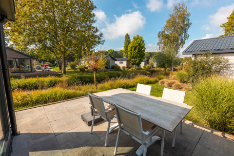 Outdoor patio with a table and chairs next to a Velthorst tiny house in Holiday park Aan de Maas, Netherlands.