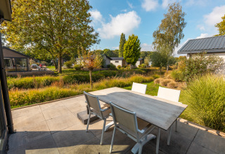 Outdoor patio with a table and chairs next to a Velthorst tiny house in Holiday park Aan de Maas, Netherlands.
