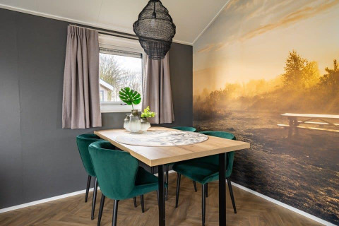 Zona pranzo moderna nella tiny house 'Velthorst' all'Holiday Park Aan de Maas con murale naturale.