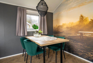 Modern dining area in tiny house 'Velthorst' at Holiday Park Aan de Maas, Netherlands, with mural wall.