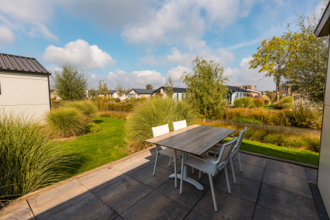 Terrasse mit Esstisch und Stühlen an der Lodge Berkel im Holiday Park Aan de Maas, umgeben von Natur.
