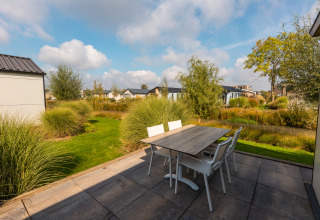 Terrasse de la lodge Berkel à Aan de Maas, Pays-Bas, avec table, chaises et verdure dans un cadre paisible.