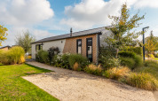 Casa vacanze moderna al Holiday park Aan de Maas, Paesi Bassi, con giardino verde e cielo azzurro.