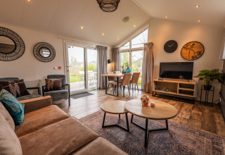 Woonkamer in lodge Berkel te Holiday park Aan de Maas, Nederland, gezellig ingericht met grote ramen en modern meubilair.