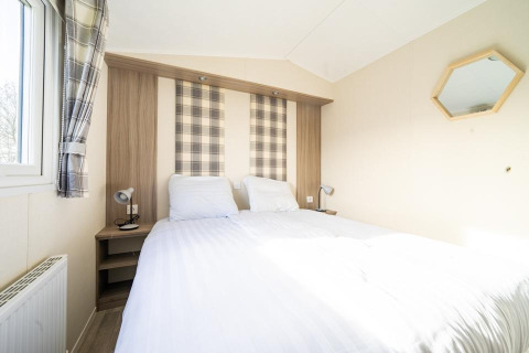Bedroom in the 'Berkel' lodge at Holiday park Aan de Maas, Netherlands, with double bed and bright decor.