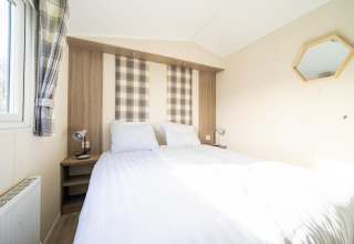 Dormitorio en la cabaña «Berkel» del parque Aan de Maas, Países Bajos, con cama doble y decoración clara.