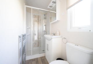 Lichte en moderne badkamer in lodge Berkel aan Holiday park Aan de Maas, met douche en wit sanitair.