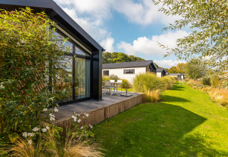 Lodge moderno «Berkel» en Holiday park Aan de Maas, Países Bajos, con terraza y jardines verdes.