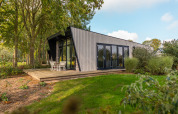 Modern Just Nature lodge at Holiday park Aan de Maas, Netherlands, surrounded by lush greenery and trees.