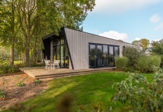Modern Just Nature lodge at Holiday park Aan de Maas, Netherlands, surrounded by lush greenery and trees.