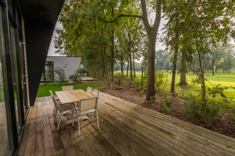 Holzterrasse mit Gartenmöbeln bei der Just Nature Lodge im Holiday Park Aan de Maas, Niederlande.