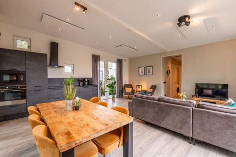 Modernes Wohnzimmer mit Küche, Essbereich und Sofa in der Just Nature-Lodge, Holiday park Aan de Maas, Niederlande.