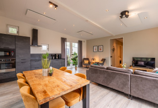 Bright living area with modern kitchen, dining table and sofa at Just Nature lodge, Holiday park Aan de Maas.