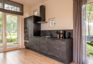 Moderne Küchenzeile in einer Lodge bei Just Nature im Ferienpark Aan de Maas, Niederlande, mit großen Fenstern.