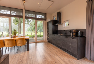 Cuisine et salle à manger modernes dans le lodge Just Nature au parc Aan de Maas, Pays-Bas, avec grandes fenêtres.