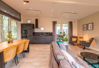 Soggiorno moderno e cucina nella lodge Just Nature, Holiday park Aan de Maas, Paesi Bassi, con luce naturale.