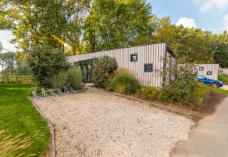 Modern Just Nature lodge at Holiday park Aan de Maas in the Netherlands, surrounded by trees and greenery.