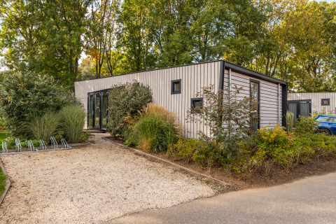 Moderna lodge Just Nature presso Holiday park Aan de Maas, Paesi Bassi, circondata dal verde.