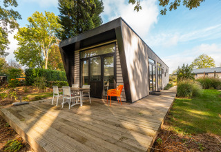 Modern lodge named Just Nature at Holiday park Aan de Maas, Netherlands, with a wooden deck and garden setting.