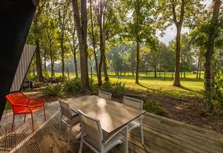 Terrace view from Just Nature lodge at Holiday park Aan de Maas, Netherlands, surrounded by woods.