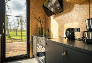 Moderne køkkenindretning i lodgen 'Just Nature' ved Holiday park Aan de Maas med udsigt over grønne marker.