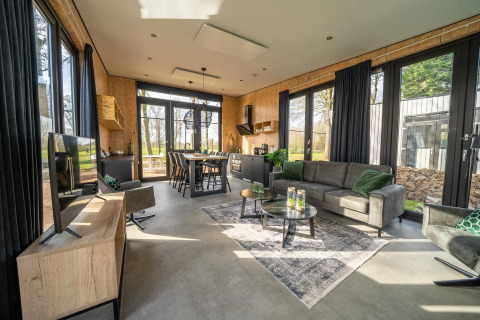 Moderne lodge-stue ved Holiday park Aan de Maas i Holland med store vinduer og stilfuld indretning.