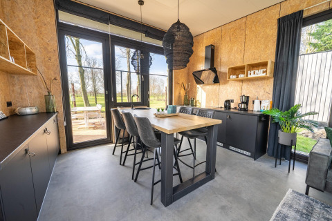 Cuisine moderne et coin repas dans un lodge au Holiday park Aan de Maas, Pays-Bas, avec grandes fenêtres sur la nature.