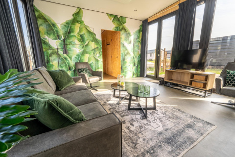 Acogedora sala de lodge en Just Nature, Holiday park Aan de Maas, con mural verde y muebles modernos.