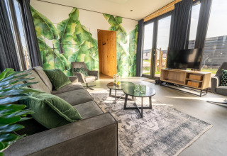 Acogedora sala de lodge en Just Nature, Holiday park Aan de Maas, con mural verde y muebles modernos.