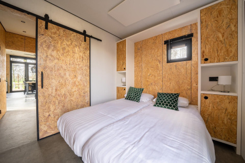 Moderne lodge slaapkamer bij Just Nature, Holiday park Aan de Maas, Nederland, OSB wanden en tweepersoonsbed.