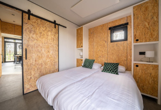 Dormitorio moderno en lodge Just Nature, Holiday park Aan de Maas, Países Bajos, cama doble y paredes OSB.