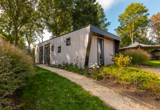 Modern Just Nature lodge at Holiday park Aan de Maas, Netherlands, surrounded by trees and gardens.