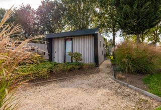 Front entrance of Just Nature lodge at Holiday park Aan de Maas in the Netherlands, surrounded by lush greenery.