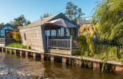 Tiny House «Havenzicht» aan het water bij De Wiedense Meren, Nederland, op een heldere, zonnige dag.