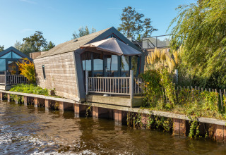 Billede af Tiny House «Havenzicht» ved vandet i ferieparken De Wiedense Meren, Holland, på en solrig dag.