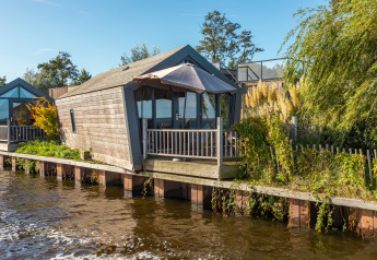 Tiny House «Havenzicht» aan het water bij De Wiedense Meren, Nederland, op een heldere, zonnige dag.