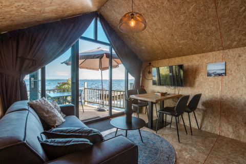 Hyggelig stue i Tiny House «Havenzicht» med udsigt over sø, udendørs terrasse og moderne indretning.
